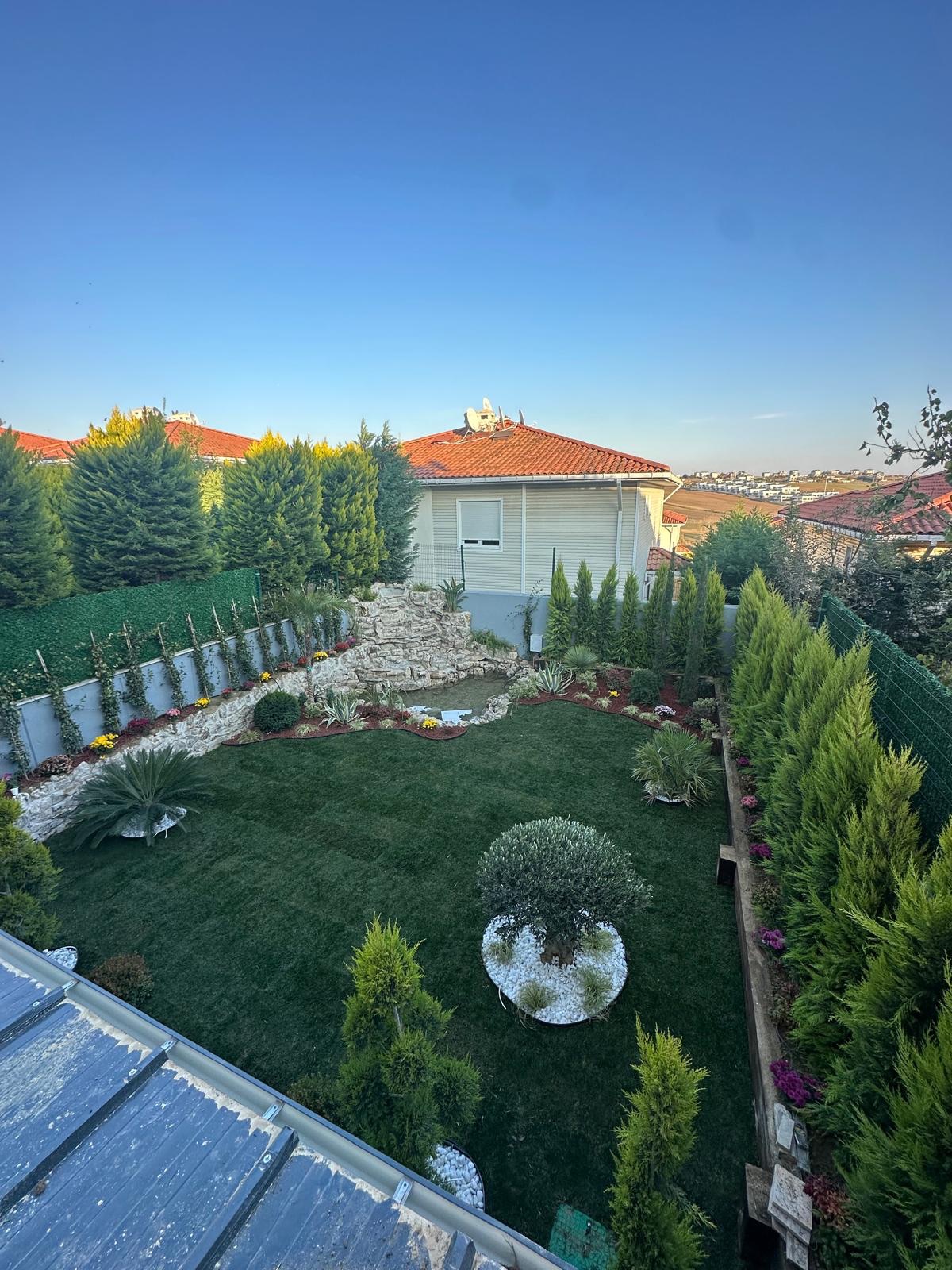 Çim, ağaç ve süs bitkileriyle tamamlanmış villa bahçesi